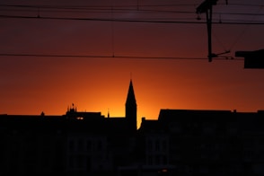 a silhouette of a building and a tower at sunset