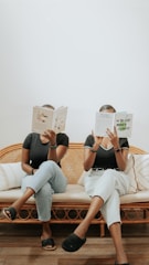 a couple of women reading books on a couch
