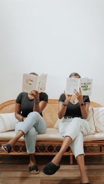 a couple of women reading books on a couch
