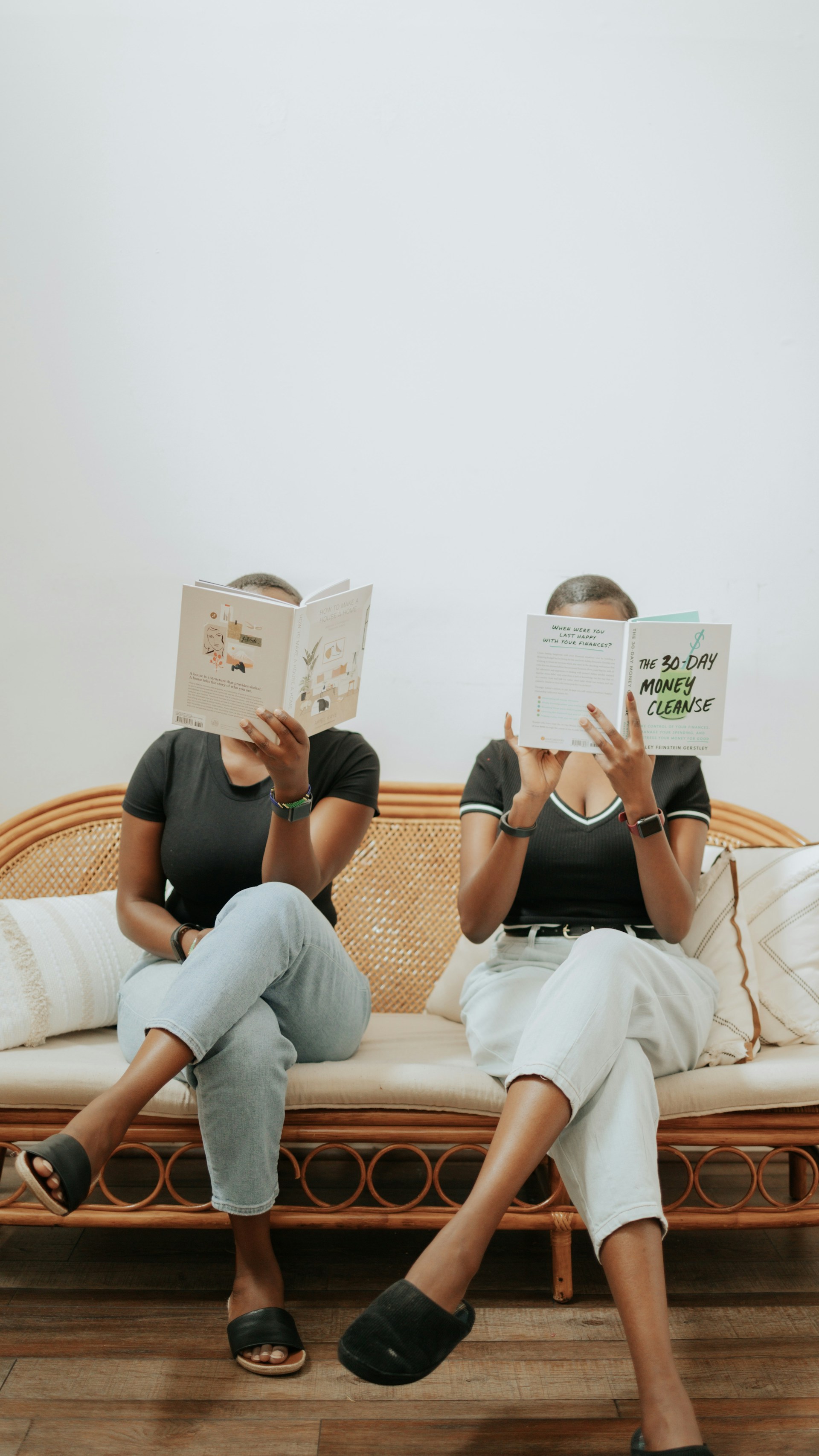 a couple of women reading books on a couch