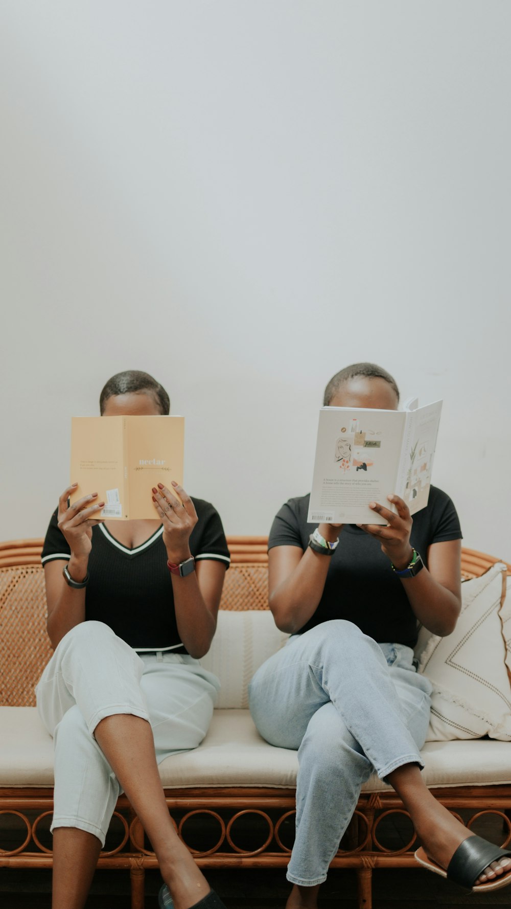 a man and woman sitting on a couch reading a book