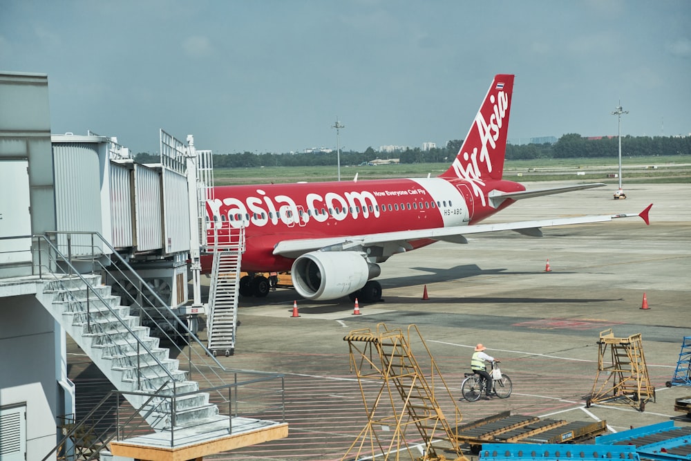 a person riding a bicycle next to an airplane at an airport