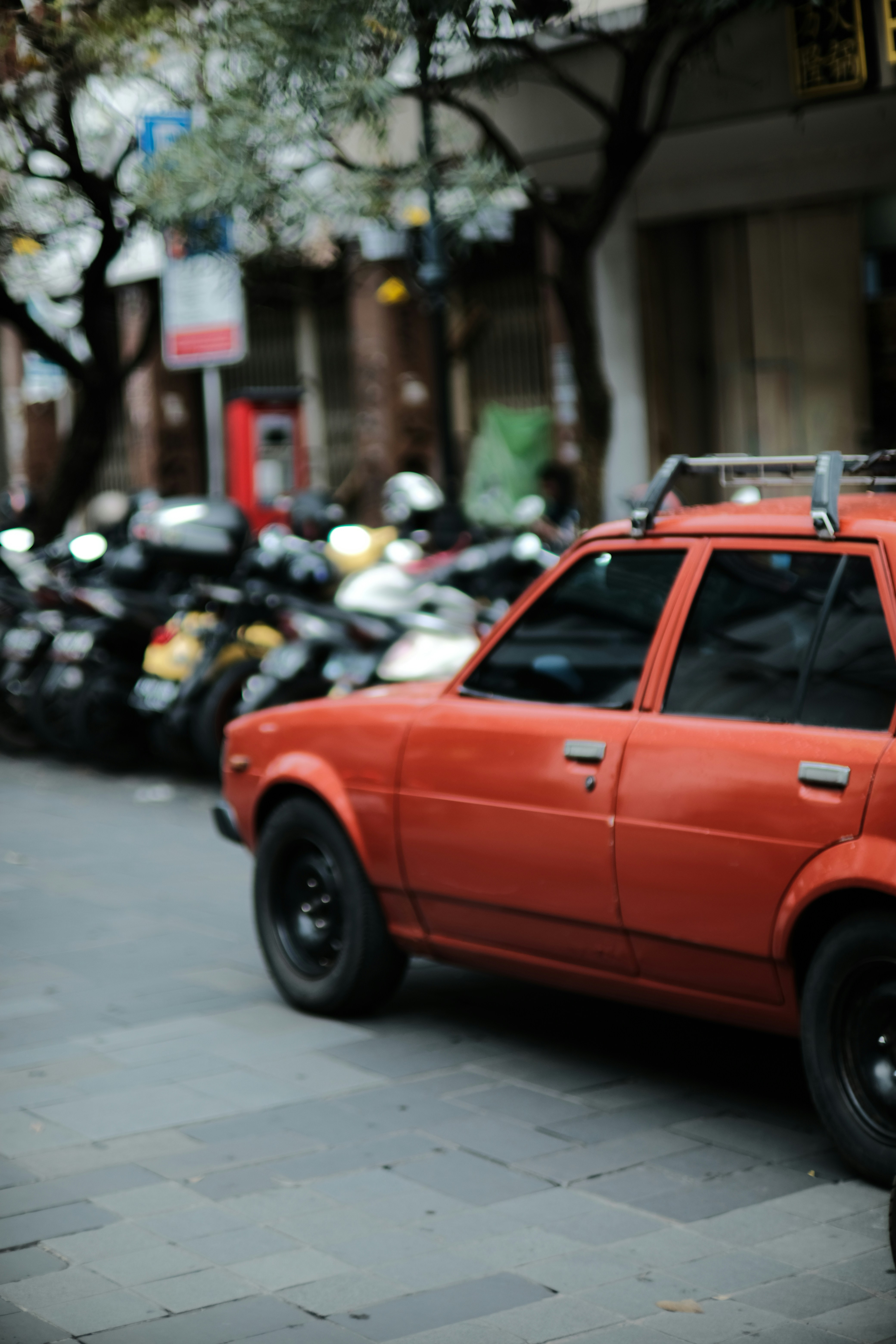 A red car parked on the side of a street photo – Free Street Image on ...