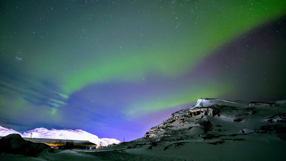 a snowy mountain with a green aurora in the sky