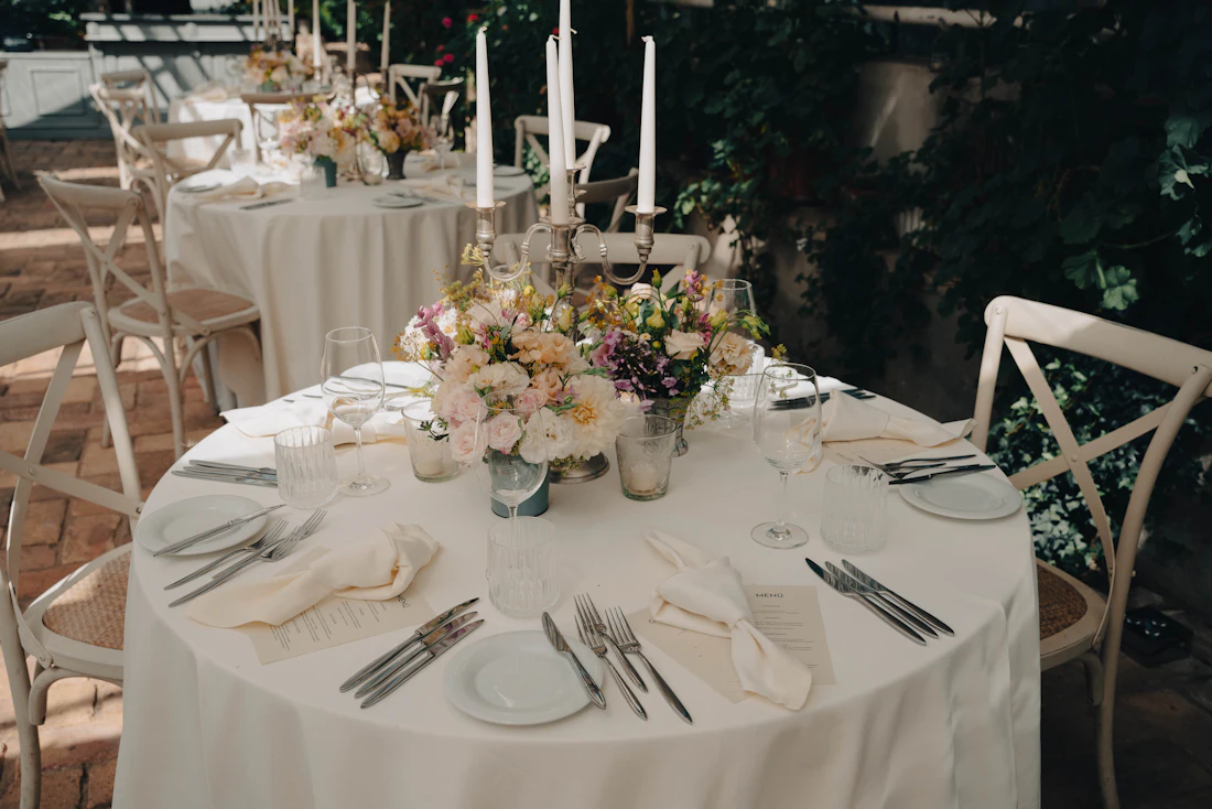 Table dressée : candélabres, bouquet, couverts alignés et cartons de menu