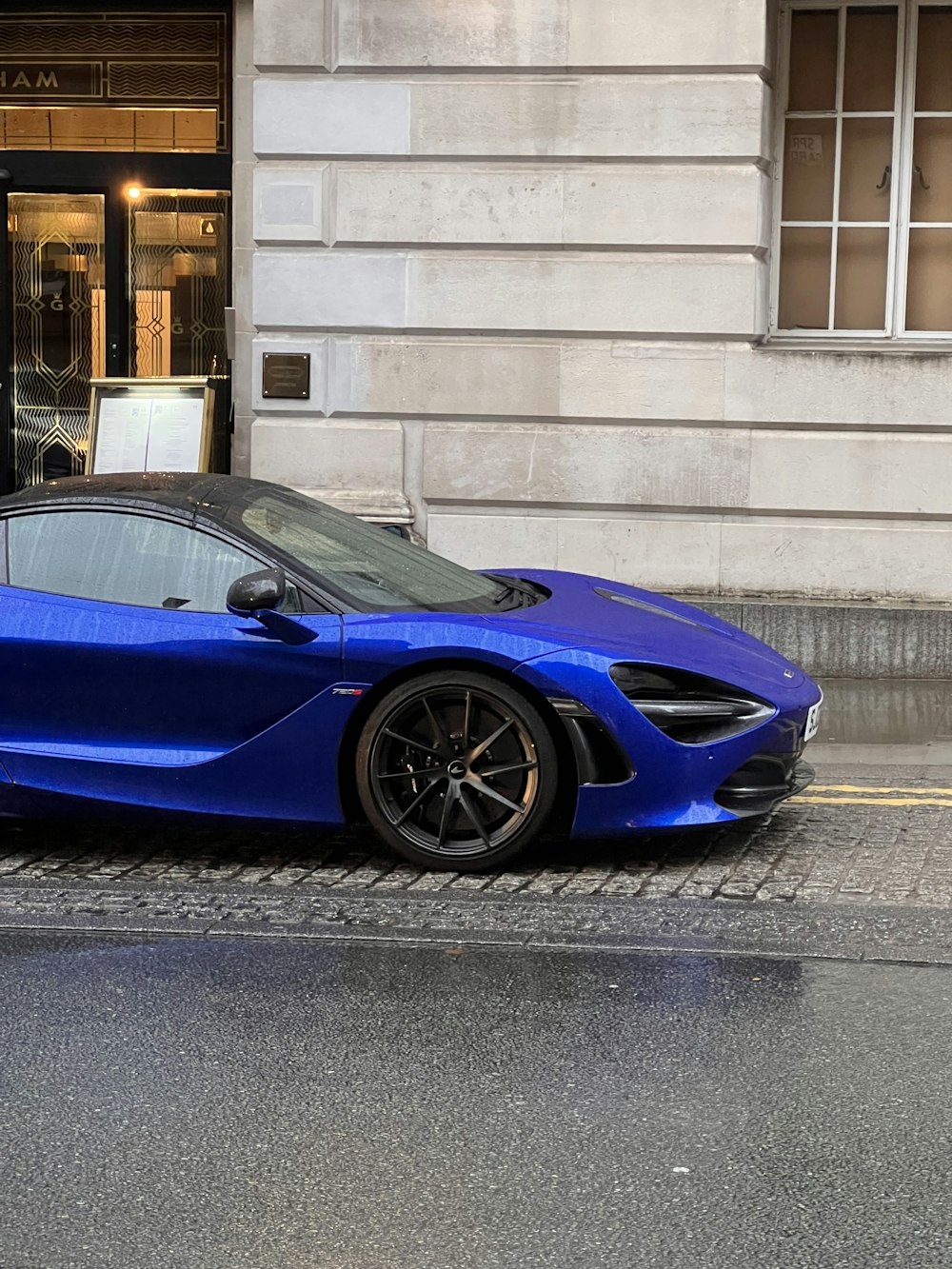 a blue sports car parked in front of a building