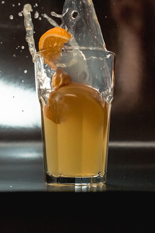 A splash of juice being poured into a glass with ice.