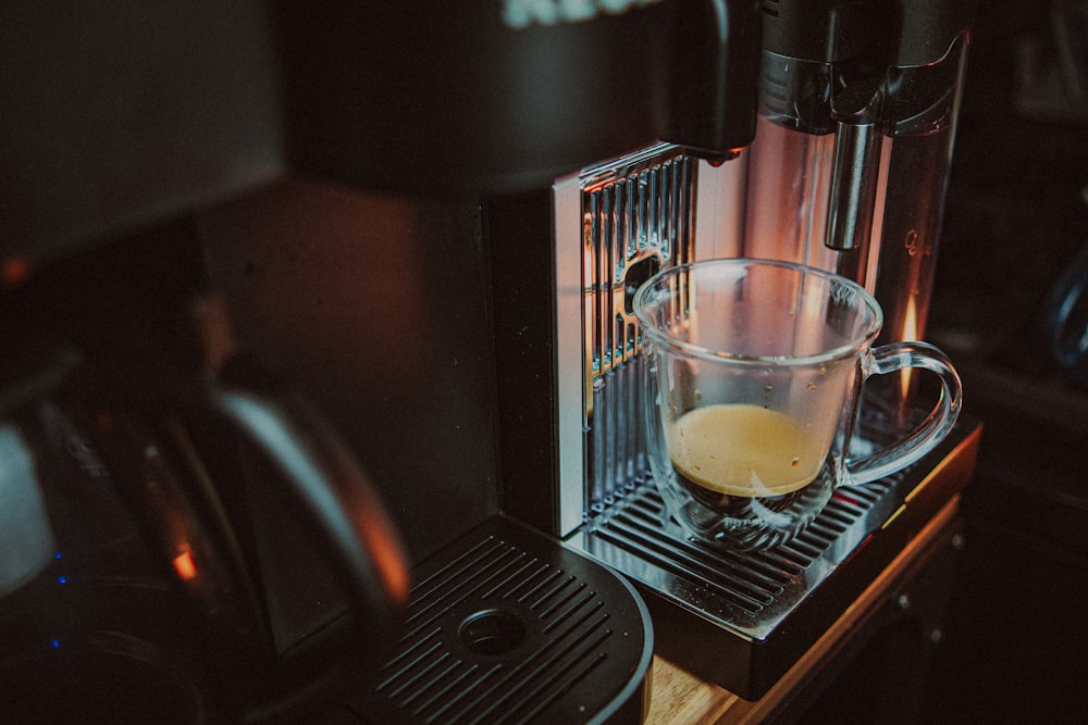 a glass of liquid on a coffee machine