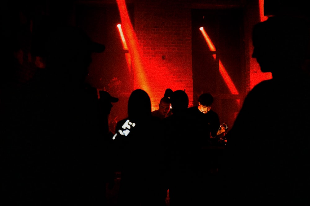 a group of people standing in a dark room with red lights