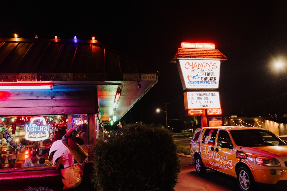 una calle con un coche y un edificio con letreros y luces