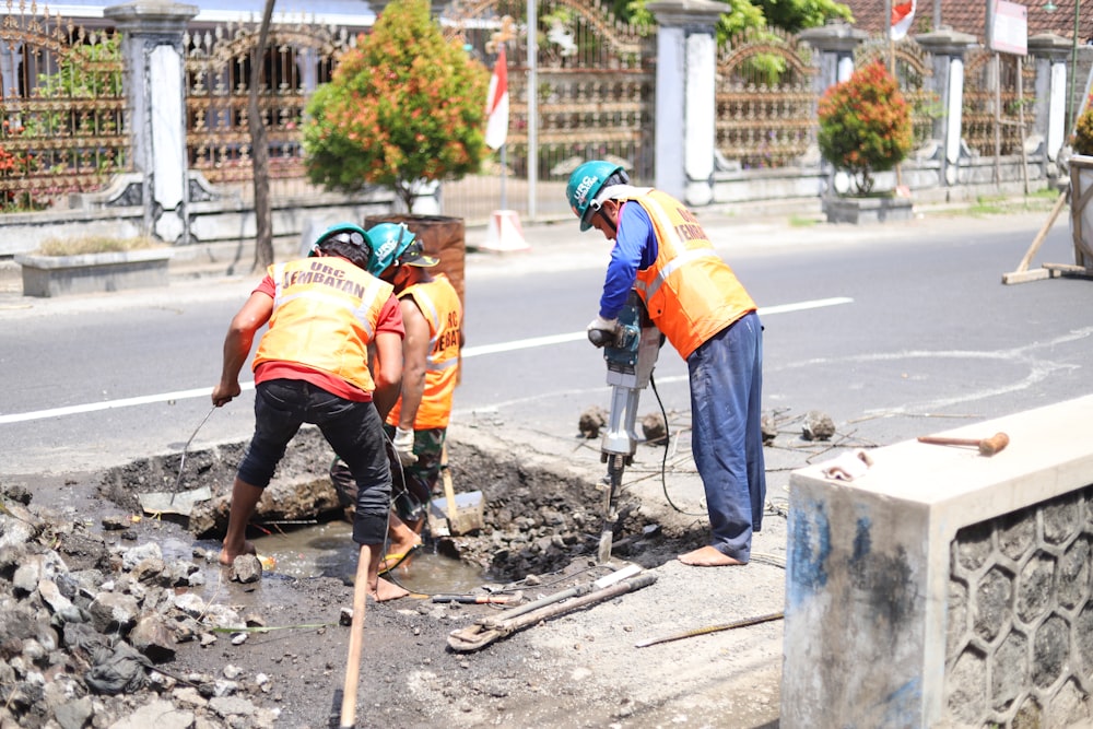 a group of men wearing safety vests working on a road