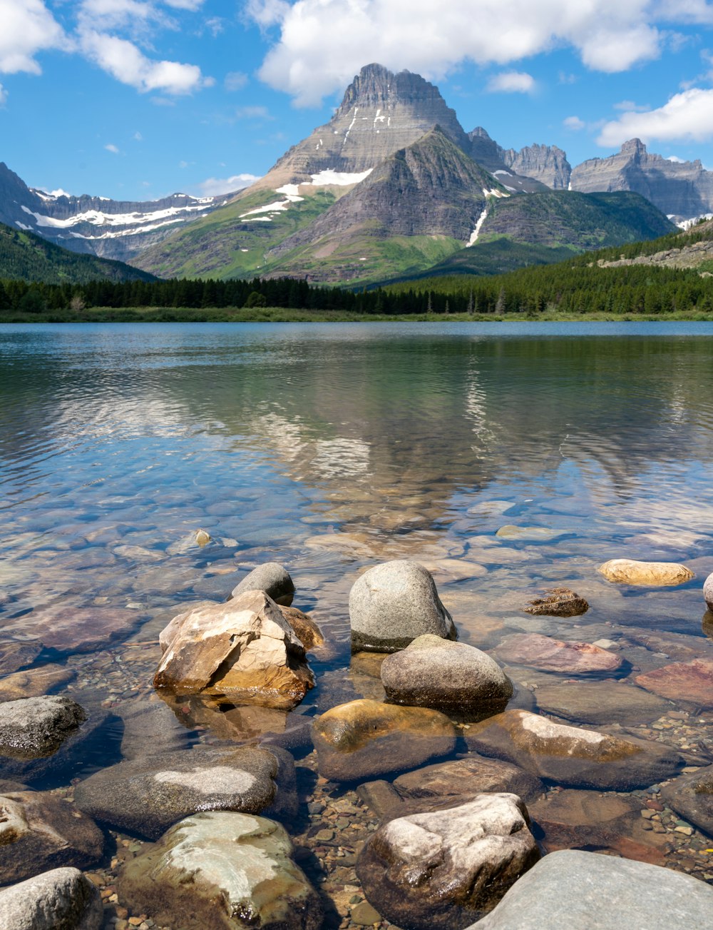 a lake with rocks and mountains in the background