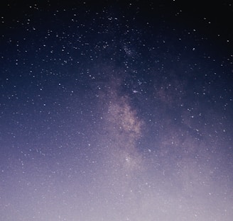 A star-filled night sky with the Milky Way galaxy prominently visible. The image captures numerous bright stars scattered across a dark, expansive sky. The galaxy's dense, light band adds a striking focal point.