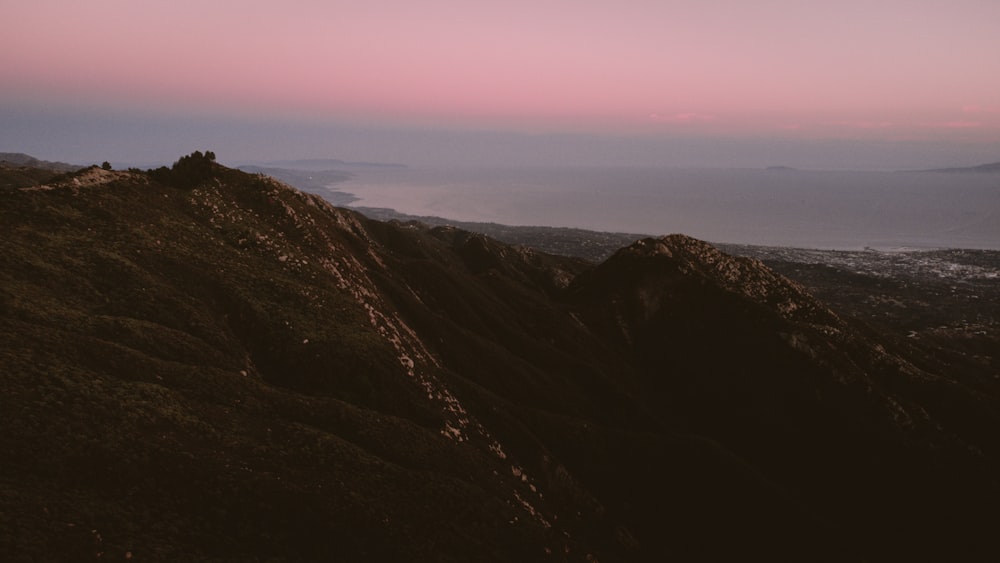 Una montaña rocosa con un cielo rosado y púrpura