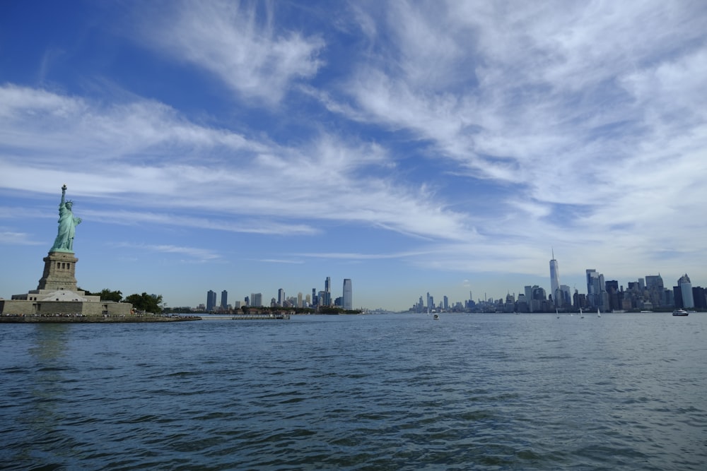 a statue on a body of water with a city in the background