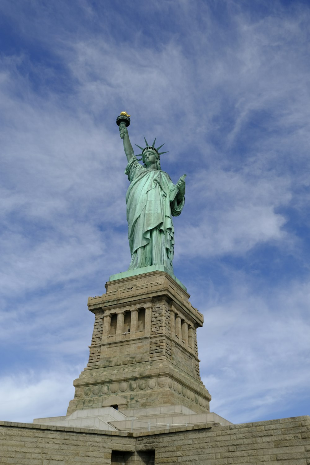 a statue of a person holding a torch with Statue of Liberty in the background