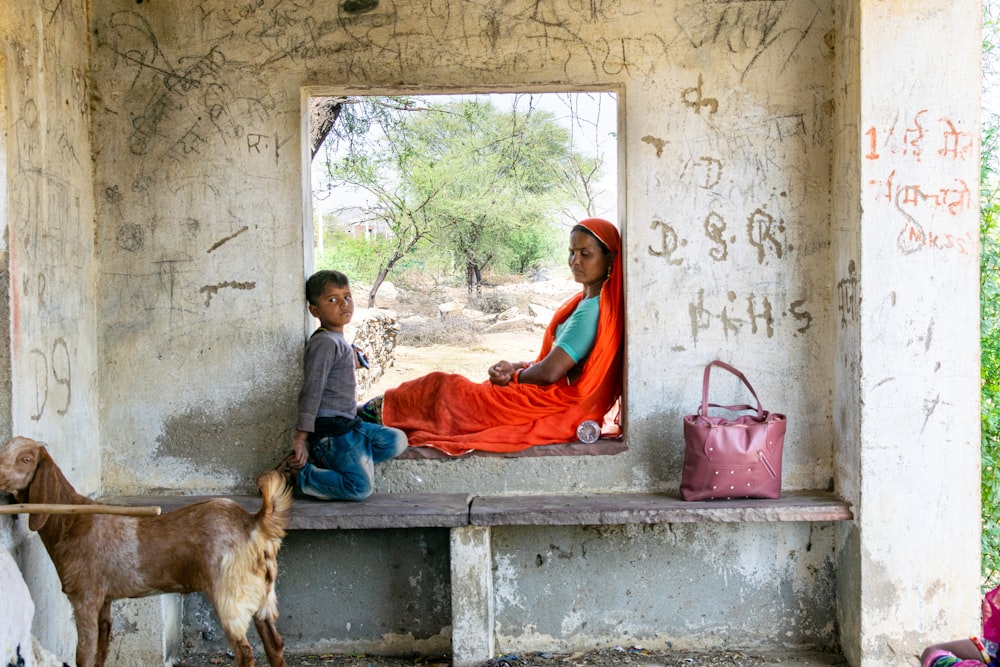 a person and a child sitting on a bench next to a dog