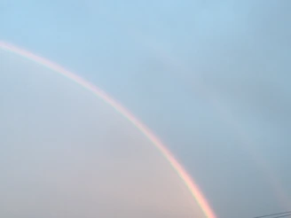 Illustration of a gentle rainbow arch with pastel colors and small shining stars.