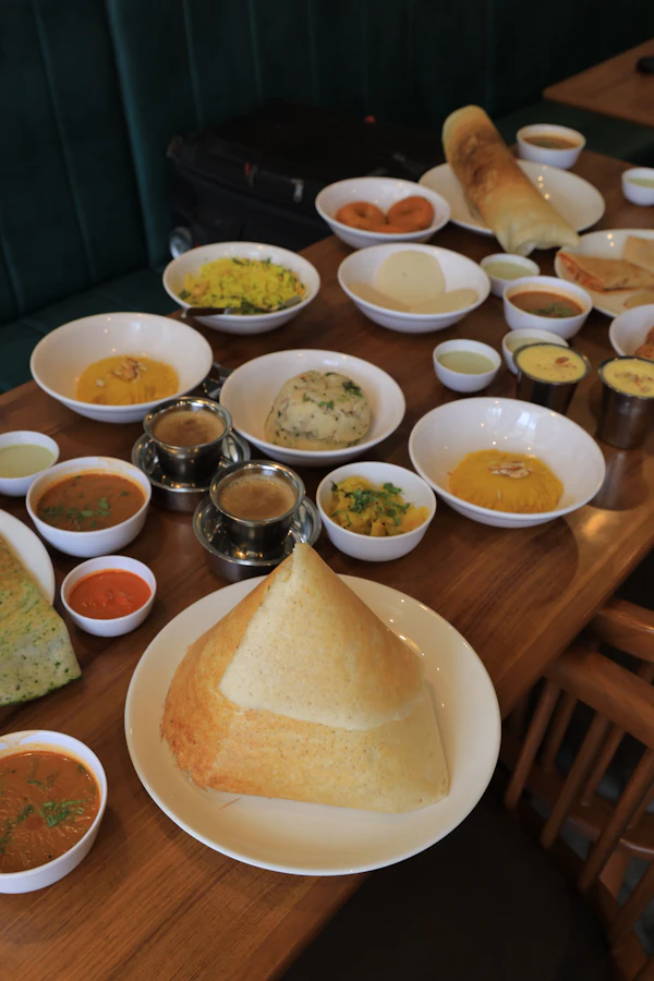 Coconut chutney and sambar in small bowls beside dosa