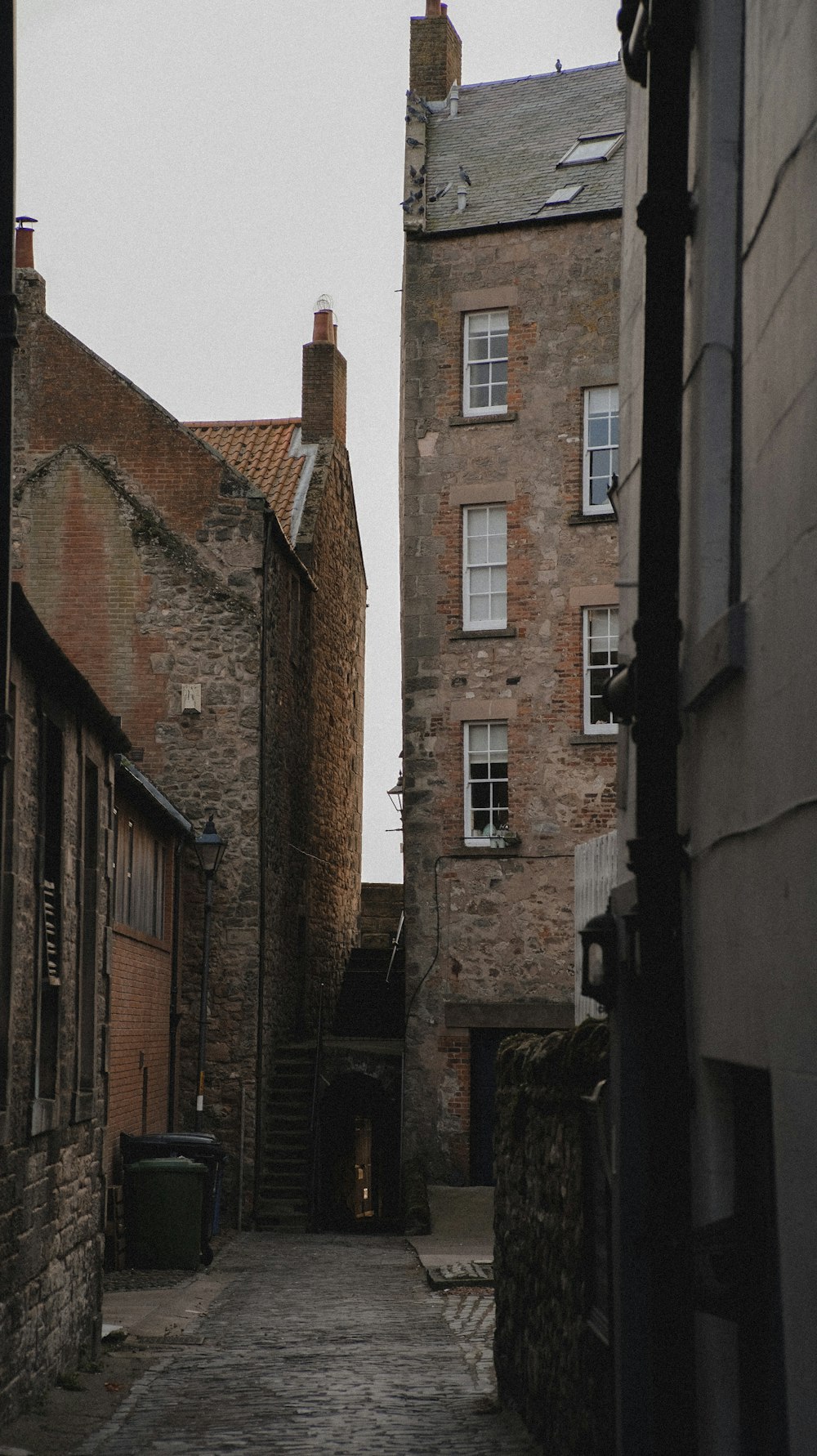 a cobblestone street between brick buildings