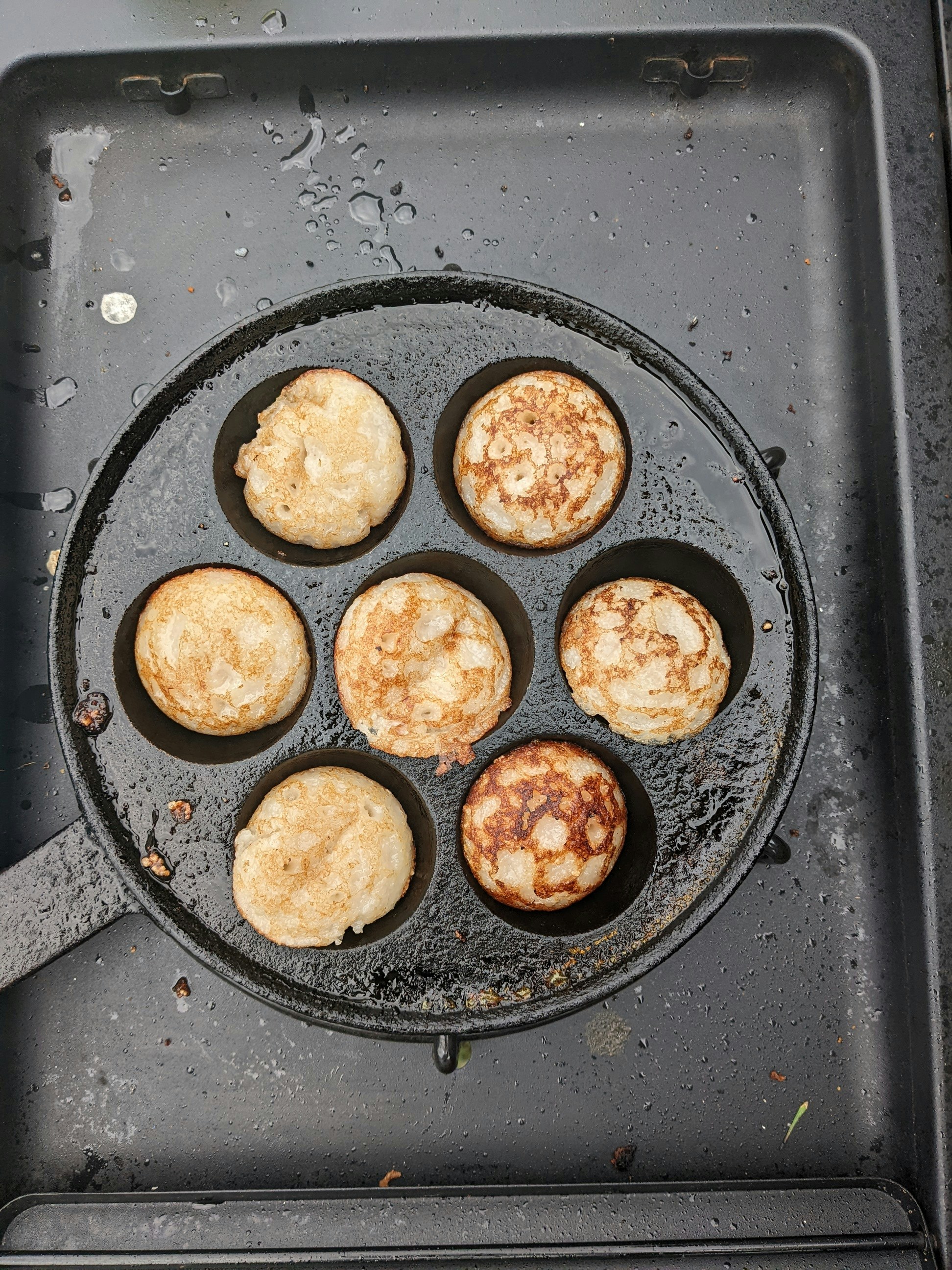 Small round coconut rice pancakes in a round iron pan
