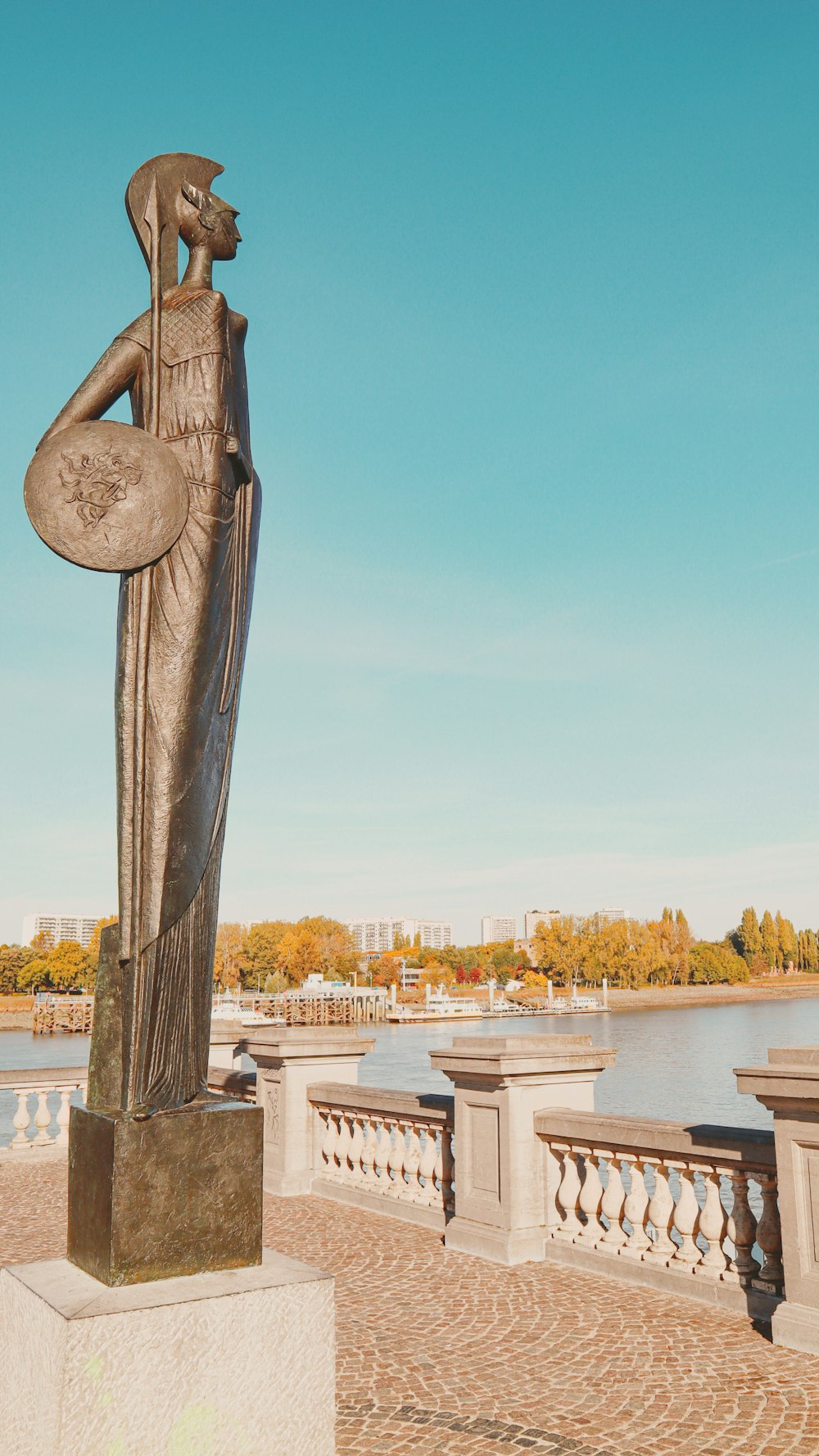 a statue of a person with a beard on a stone pillar by a body of water