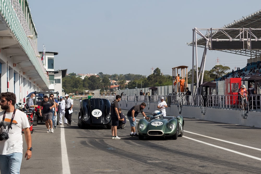 um grupo de pessoas em torno de um carro de corrida em uma pista