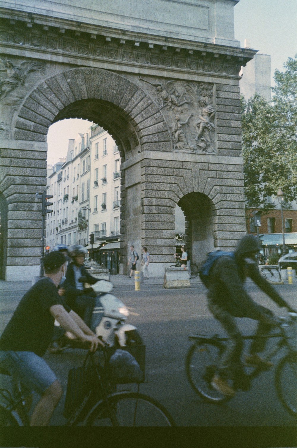 a group of people ride bikes under a stone arch