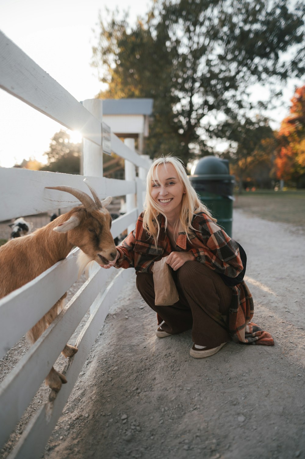a person kneeling next to a goat