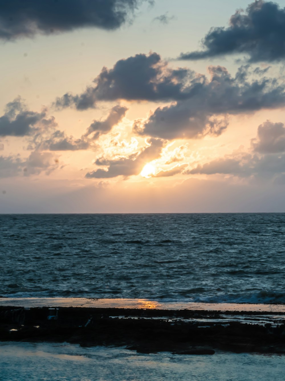 a beach with a body of water and clouds in the sky