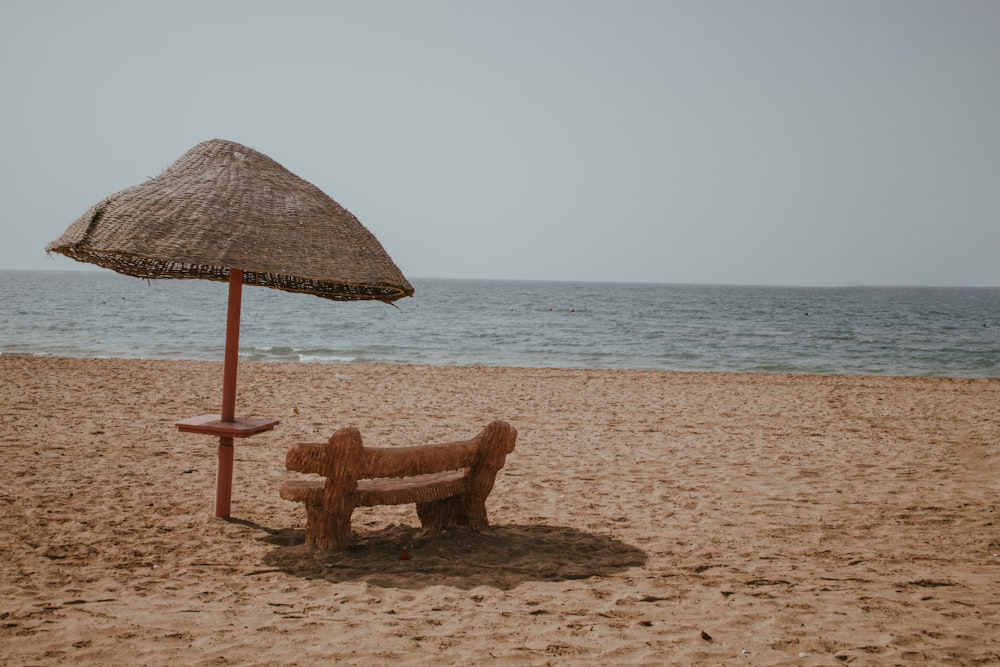 a couple of benches sit under an umbrella on a beach