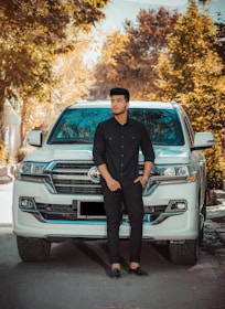 A confident agent standing by a sleek car outside a stylish suburban home on a sunny day.