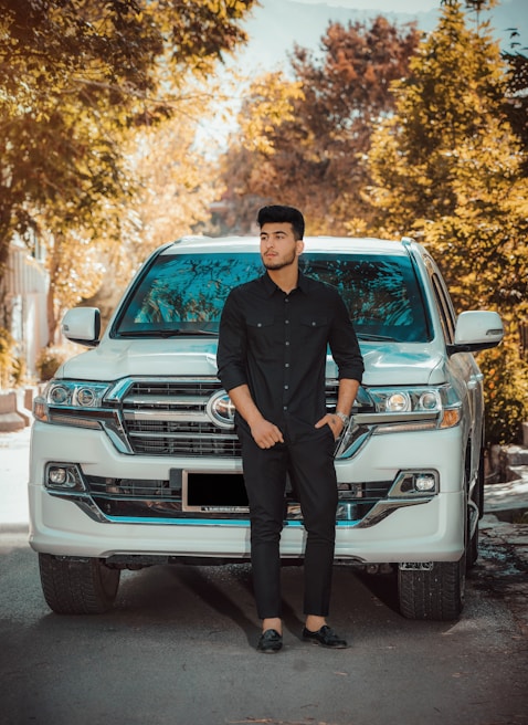 A professional driver in uniform standing confidently beside a clean car