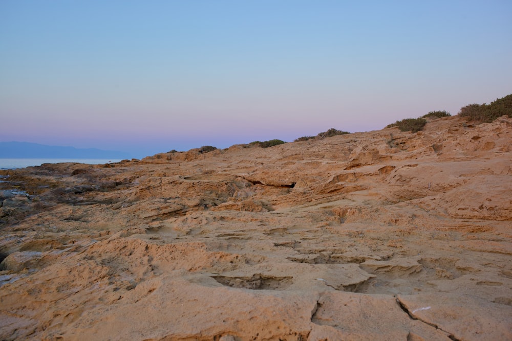 a sandy area with a hill in the background