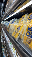 Shelves filled with colorful dairy products in a bright supermarket aisle.