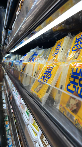 A selection of dairy products like milk cartons, cheese blocks, and yogurt cups on a clean white background.