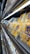 A supermarket shelf displays neatly organized packs of cheese in transparent plastic packaging. The yellow and blue design on the packaging stands out. Below these, a lower shelf holds containers of various dairy products. The lighting is bright, highlighting the products.