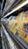 A supermarket shelf displays neatly organized packs of cheese in transparent plastic packaging. The yellow and blue design on the packaging stands out. Below these, a lower shelf holds containers of various dairy products. The lighting is bright, highlighting the products.