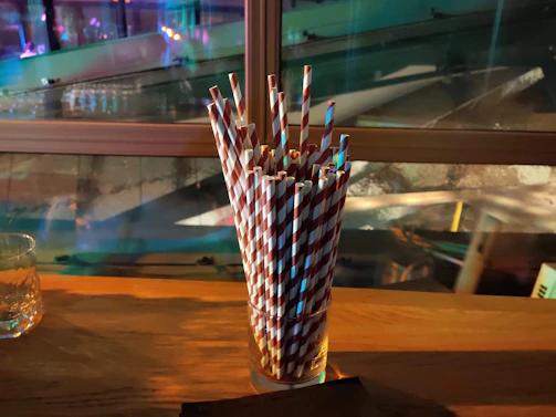 An assortment of eco-friendly paper straws and cutlery arranged artistically on recycled paper sheets.