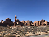 Open desert road framed by red rock formations under a clear blue sky
