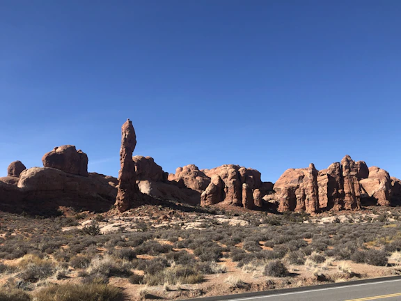 Open desert road framed by red rock formations under a clear blue sky