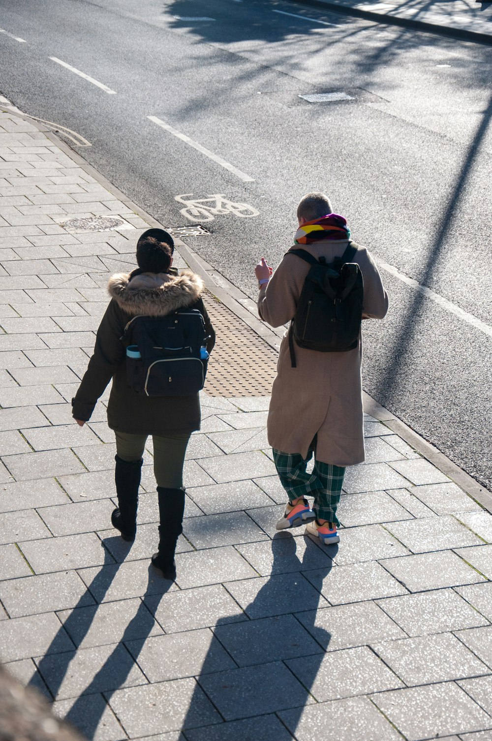 two people walking on a sidewalk