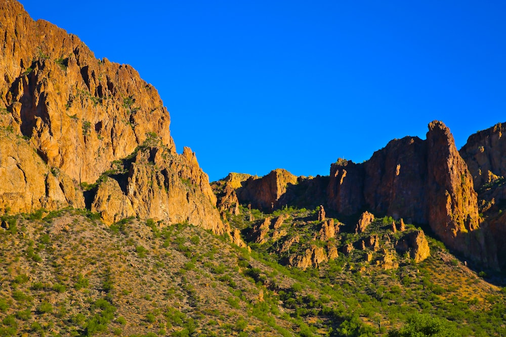 a rocky mountain with green grass