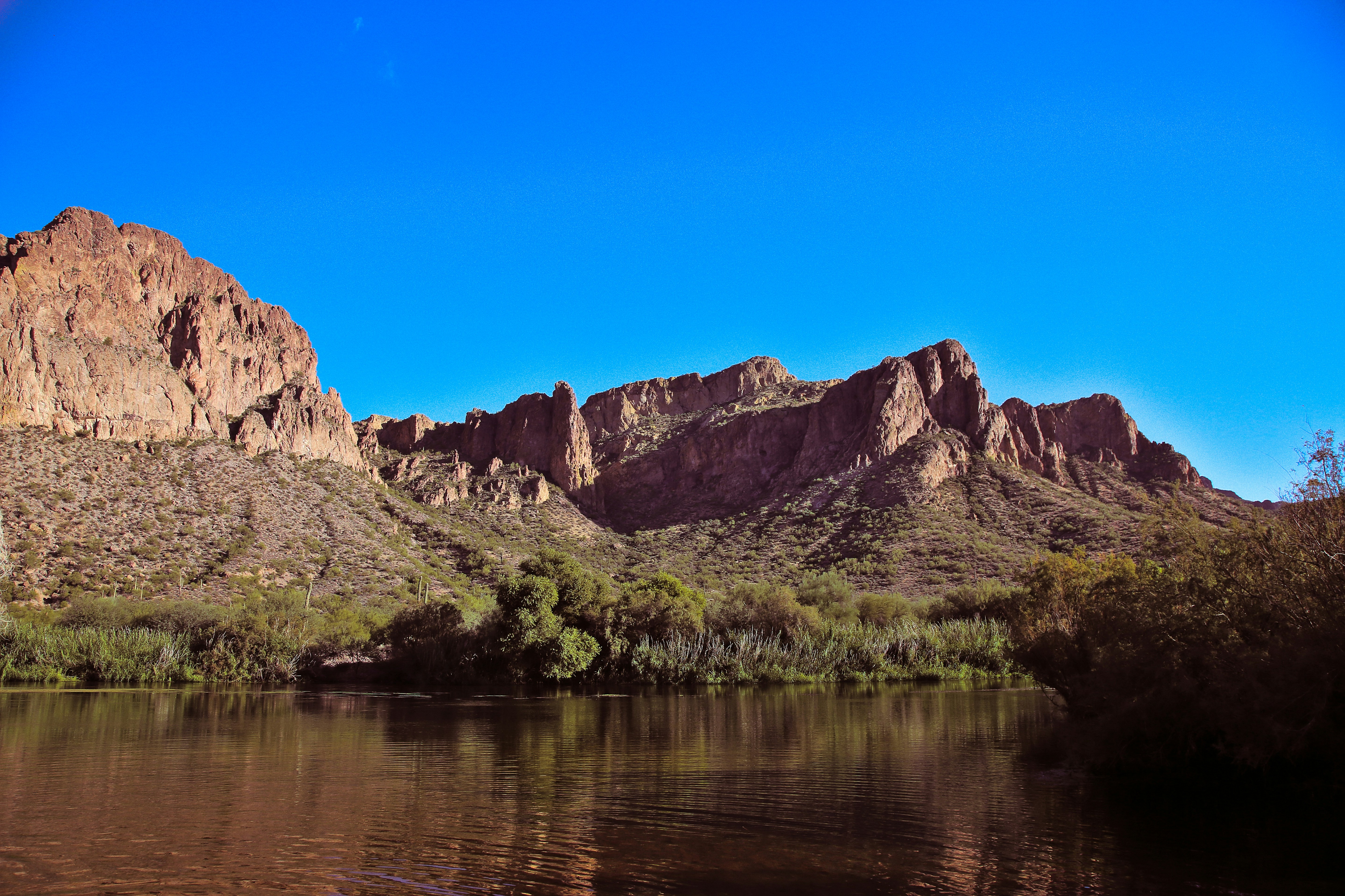 a body of water with a rocky mountain in the background