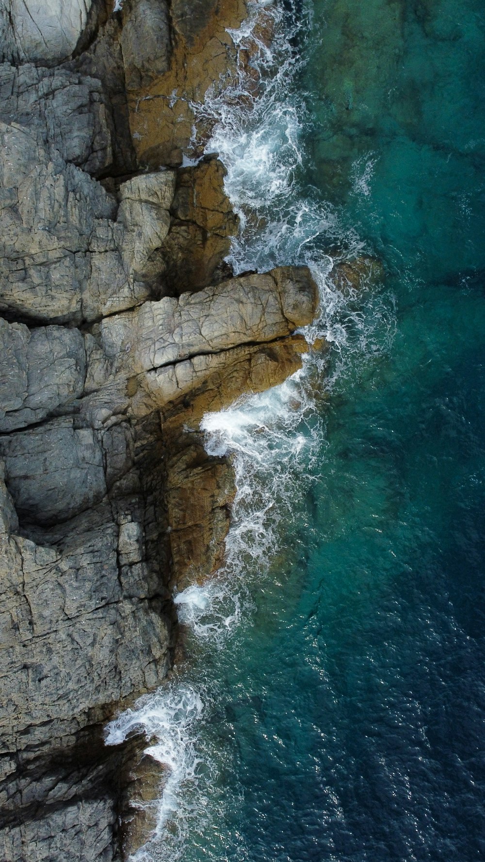 a rocky cliff with a body of water below