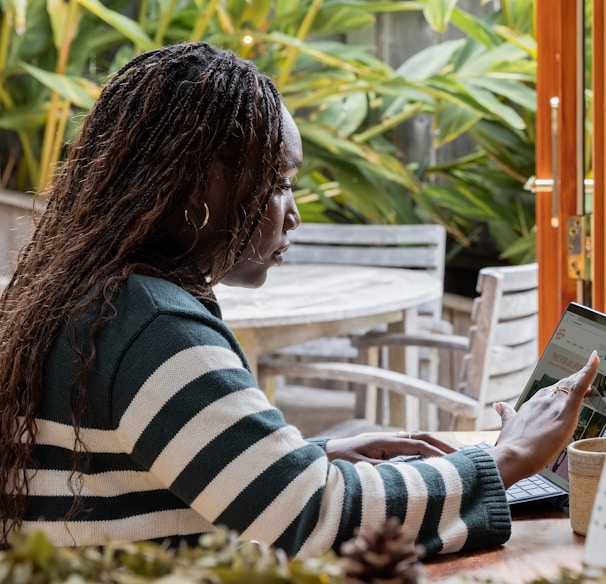 a person standing in front of a laptop computer talking on a cell phone