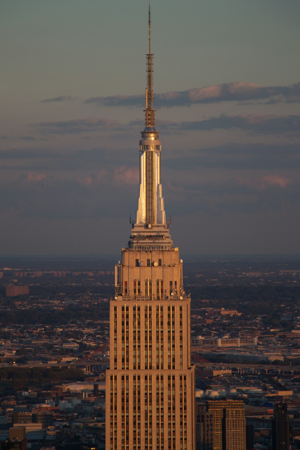 a tall building with a pointy top with Empire State Building in the background