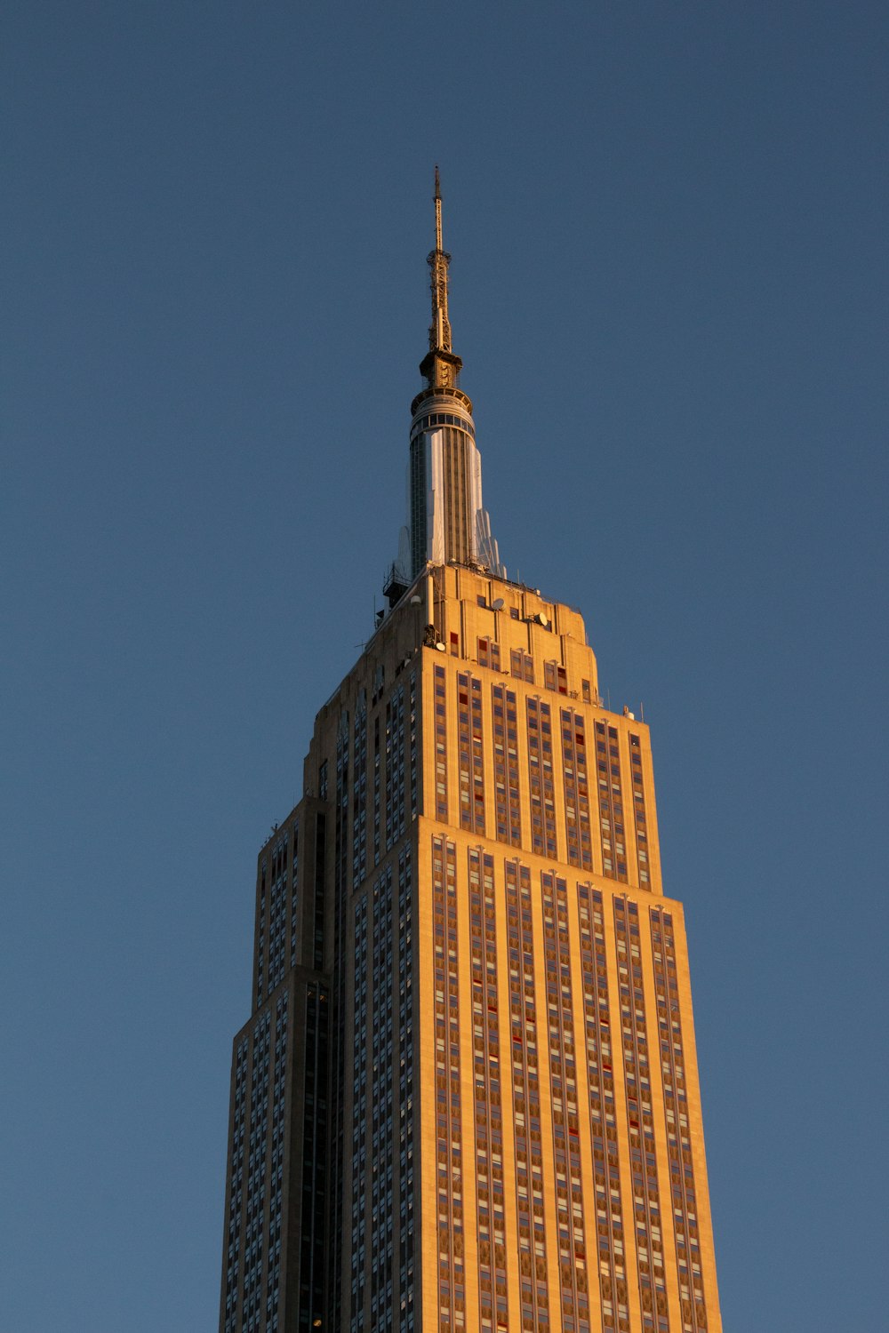 a tall building with a pointy top with Empire State Building in the background