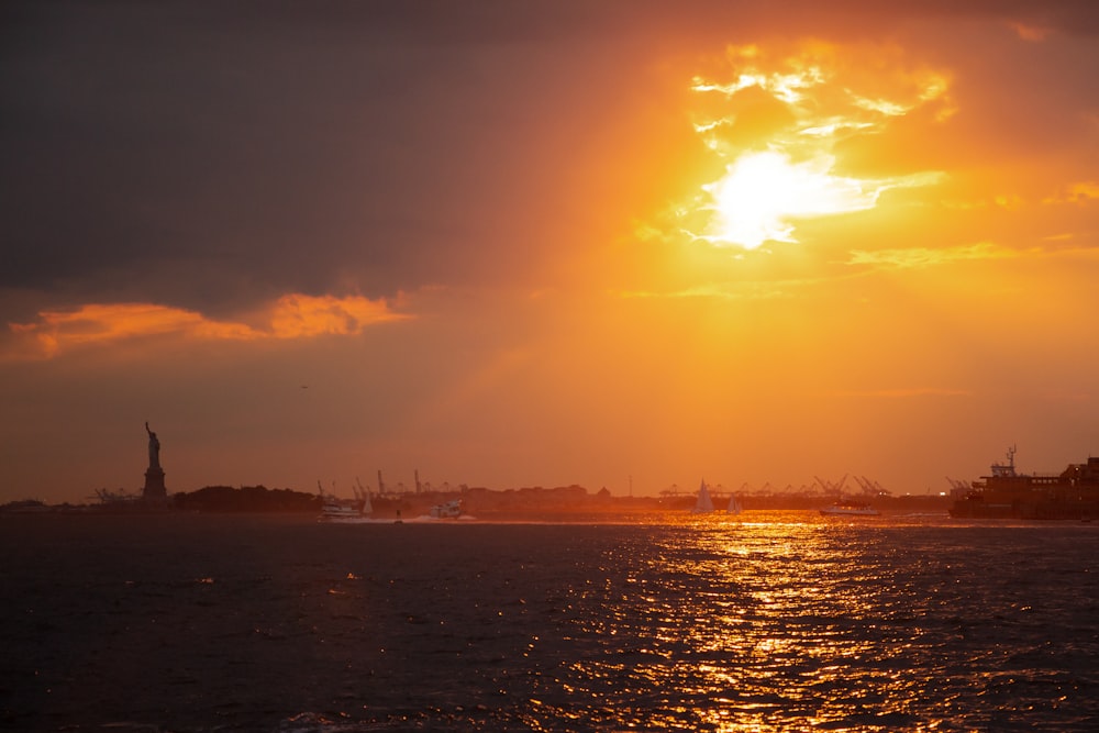 a body of water with a statue in the middle and a sunset