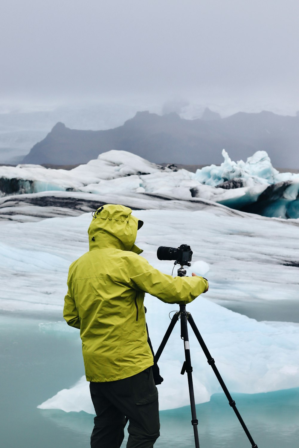 a person with a camera on a tripod in front of a snowy mountain
